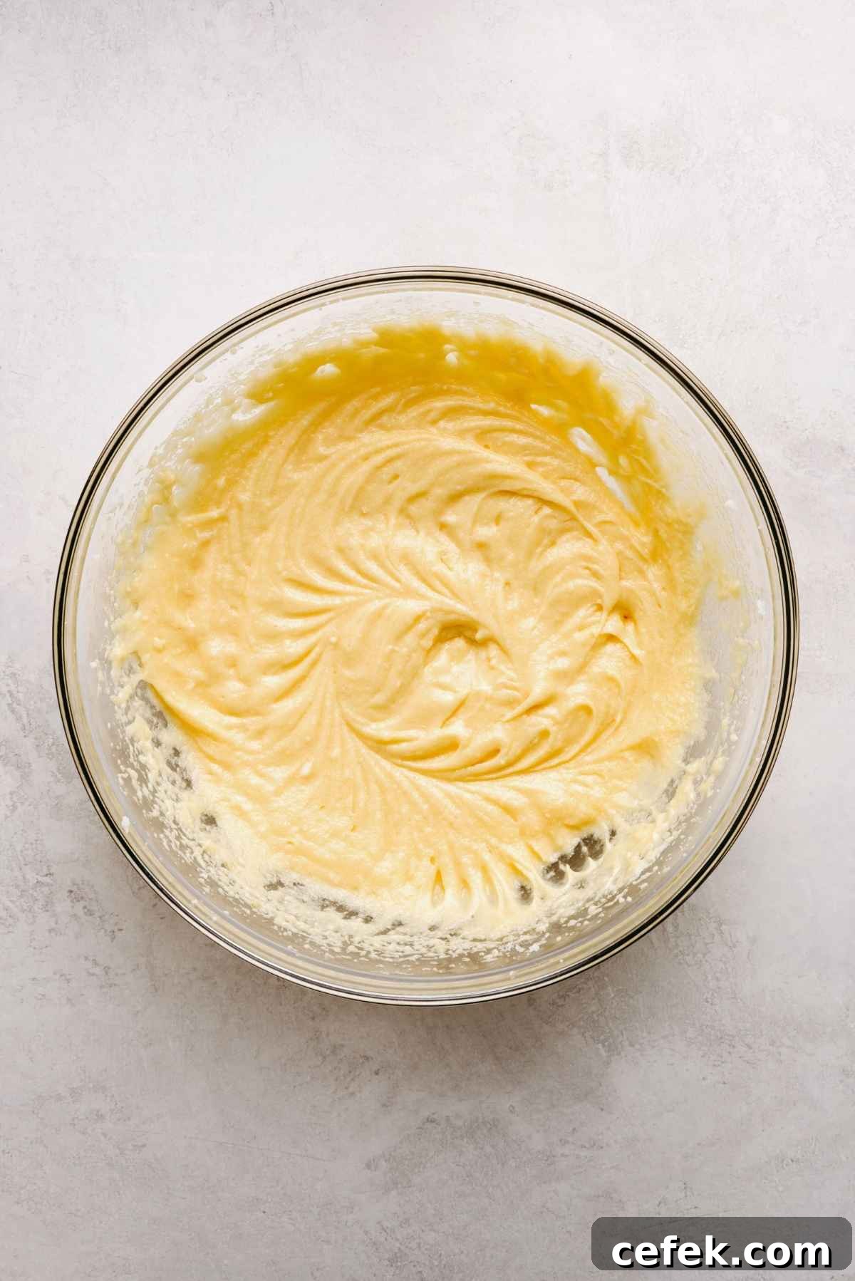 Classic Four-Egg Yellow Sheet Cake with Chocolate Frosting 9 Vanilla extract and eggs added to the yellow cake batter mixture in a large glass bowl.