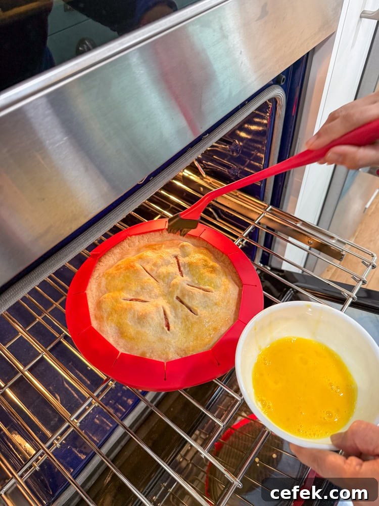 Classic Strawberry Rhubarb Pie Recipe 13 brushing egg wash into the pie