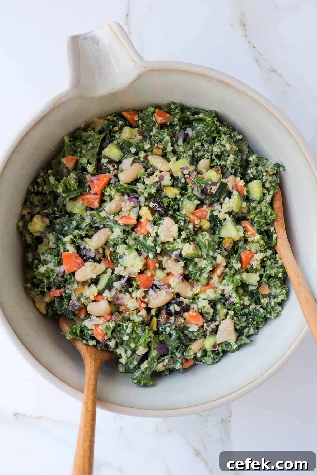 White Bean and Kale Salad with Creamy Avocado Dressing 2 Kale salad in a bowl with mixing spoons.