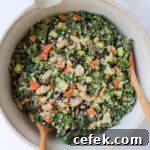 Kale salad in a bowl with mixing spoons.