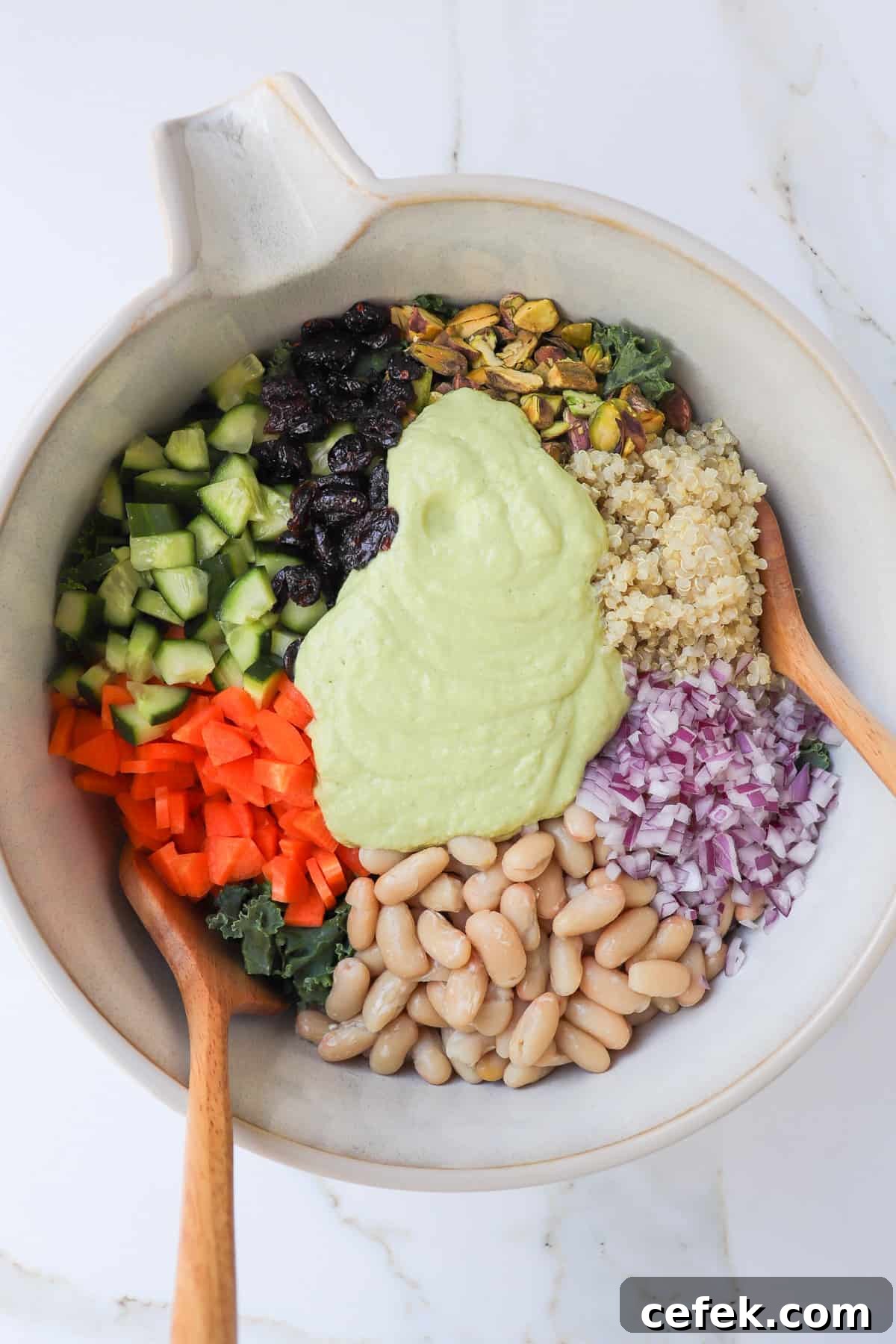White Bean and Kale Salad with Creamy Avocado Dressing 7 Salads in gradients in a bowl with the avocado dressing poured in the middle.