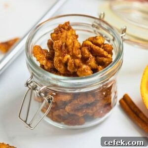 Crunchy Candied Walnuts for Salads, Desserts & Snacks 2 Small jar of homemade candied walnuts next to fresh orange and cinnamon sticks.